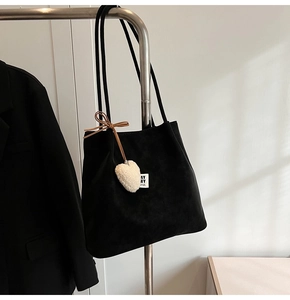 Detail of black suede tote bag with heart plush charm and brown bow knot on hanger