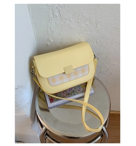Gros plan d'un sac bandoulière en cuir jaune clair avec panneau damier sur tabouret