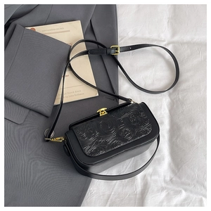 Close-up of black retro shoulder bag featuring floral embossing and gold metal lock detail