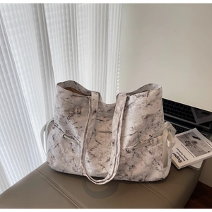 Détail d'un sac cabas en toile à motif marbre avec nœuds en satin blanc et fermoir en métal