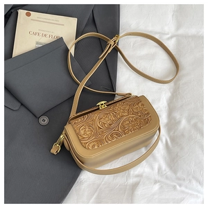 Detail of floral embossed crossbody bag with golden buckle on neutral background