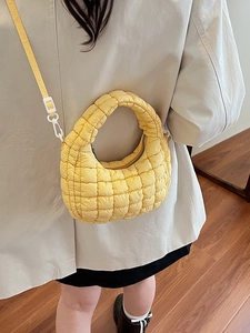 Quilted yellow puffer shoulder bag with a square pattern and detachable strap on model
