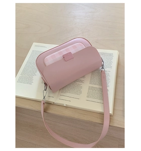 Détail du sac en similicuir rose avec motif à carreaux posé sur un livre ouvert