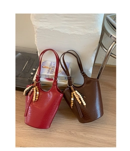 Detailed close-up of crocodile textured bucket bags with decorative wooden bead tassels