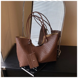 Détail d'un sac cabas marron à texture tressée avec pochette assortie sur surface miroir