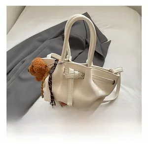 Détail d'un sac à main nuage blanc avec un porte-clés ours en peluche marron attaché