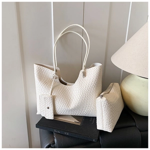 Détail d'un ensemble de sacs tissés crème avec pochette assortie sur décor de livres