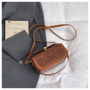 Detailed view of brown vintage crossbody bag with embossed floral pattern and gold lock