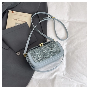 Detail of light blue crossbody bag with vintage floral embossing and golden buckle