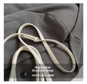 Détail de la bandoulière réglable sur le sac seau en cuir blanc avec boucle argentée