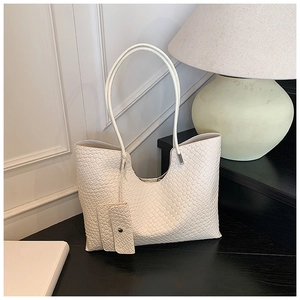 Détail du sac cabas blanc à texture tressée avec accents argentés et pochette