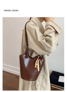 Detail of a brown crocodile pattern bucket bag featuring a colorful wooden bead charm
