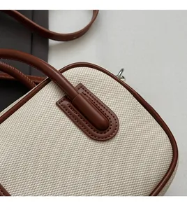 Close-up of contrast woven canvas and brown leather stitching on minimalist handbag