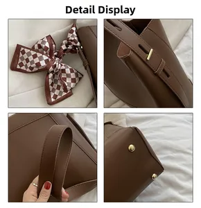 Detail view of brown tote bag with gold hardware, adjustable strap, and checkered scarf