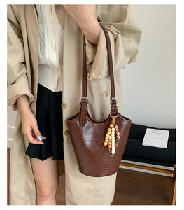 Detail of vintage brown bucket bag featuring crocodile pattern and wooden bead charm accessory