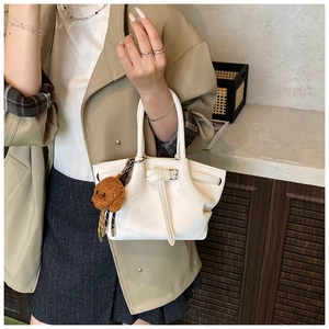 Détail du sac à main blanc crème avec cordon nœud et breloque ours en peluche marron