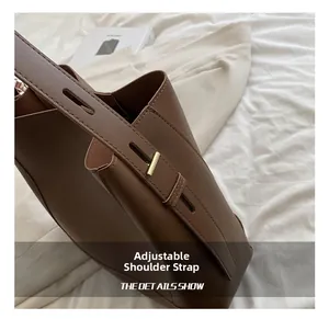 Detail of adjustable brown leather shoulder strap with gold buckle on tote bag