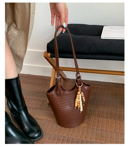 Detail of dark brown faux crocodile bucket bag with beaded tassel and adjustable strap