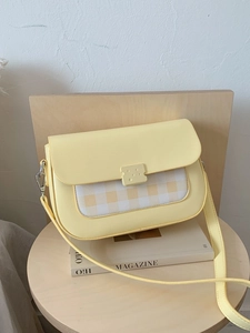 Sac bandoulière vichy jaune chic avec boucle fromage sur un siège en bois minimaliste