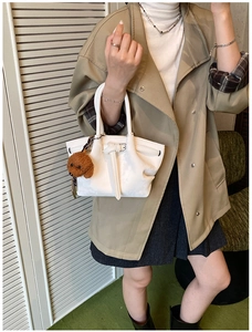 Gros plan sur sac à main en cuir blanc avec sangles décoratives et pendentif chien