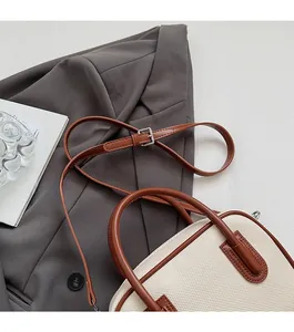 Detail of adjustable leather strap and canvas fabric on a stylish crossbody bag