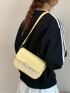Sac bandoulière jaune pâle avec rabat à carreaux porté par un mannequin en mode urbain