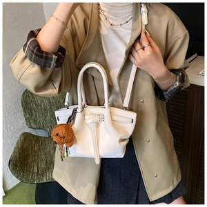 Détail du sac seau blanc avec boucle décorative et breloque en peluche caniche marron