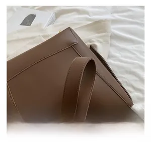 Detail view of the wide leather shoulder strap and neat stitching on a brown tote bag