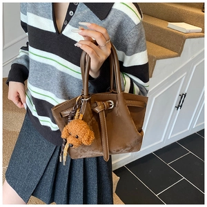 Détail du cabas en daim marron foncé avec boucle et pendentif chien en peluche