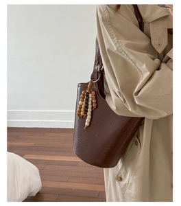 Detail of dark brown stone pattern bucket bag with decorative wooden beaded tassel