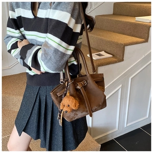 Sac à main en daim marron avec bandoulière et pendentif ours sur l'escalier