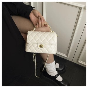 Détail du sac bandoulière matelassé blanc crème avec son fermoir rotatif en métal doré