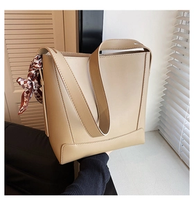 Close-up of beige leather bucket bag featuring a decorative plaid silk scarf on the side