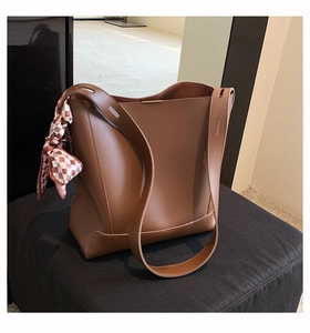 Close-up of brown leather tote bag featuring a red and white checkered silk scarf detail