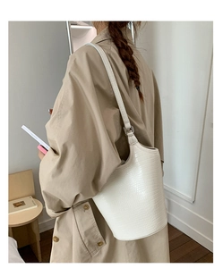 Detail of white bucket bag featuring elegant crocodile embossed texture and adjustable strap