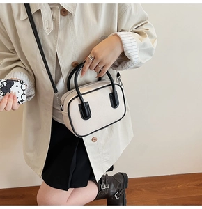 Detail of a minimalist cream PU leather crossbody bag with contrasting black handles