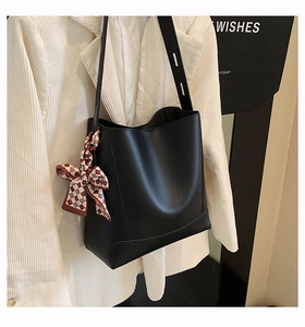 Detail of black bucket tote bag with plaid silk scarf tied on strap for daily commuting