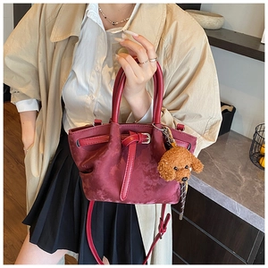 Détail du sac seau bordeaux en daim avec un pendentif mignon d'ours en peluche brun