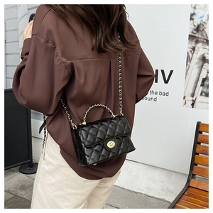 Détail du sac à bandoulière matelassé avec chaîne dorée et fermoir pivotant sur modèle