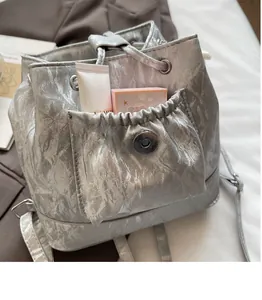 Detail of silver metallic textured backpack featuring front pocket with magnetic snap closure