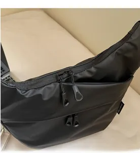 Close-up of black nylon shoulder bag featuring smooth double zippers and side woven label