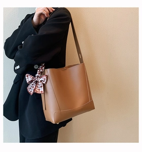 Close-up of caramel bucket bag with checkered silk scarf on handle for office look