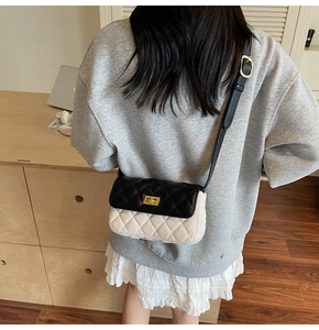 Detail of a chic quilted crossbody bag featuring a two-tone black and beige contrast design