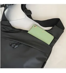 Detail showing the large front zipper pocket of this black nylon crossbody bag with a phone