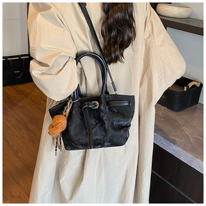 Détail d'un sac seau noir avec charm d'ours marron porté par un mannequin de dos