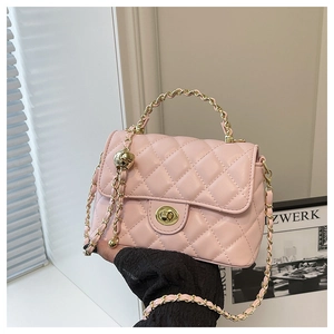 Détail du sac à bandoulière matelassé rose avec chaîne dorée et fermoir tournant en métal