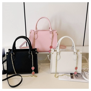 Détail de petits sacs fourre-tout noir, rose et blanc avec breloque fraise en métal
