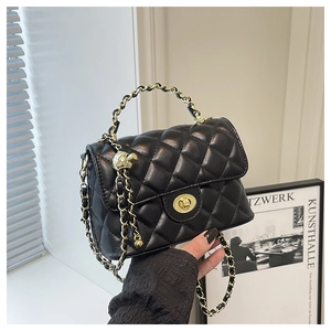 Détail du sac matelassé noir en cuir avec fermoir doré et bandoulière en chaîne tressée