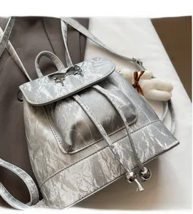Detail view of silver backpack with butterfly buckle and plush bear keychain ornament