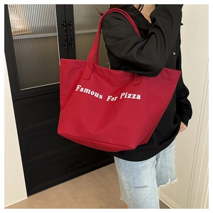Dettaglio di una borsa tote in tela rossa con stampa Famous For Pizza e doppi manici robusti